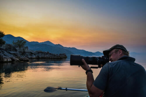 Wildlife photographer during sunset on kayak in Skadar Lake.